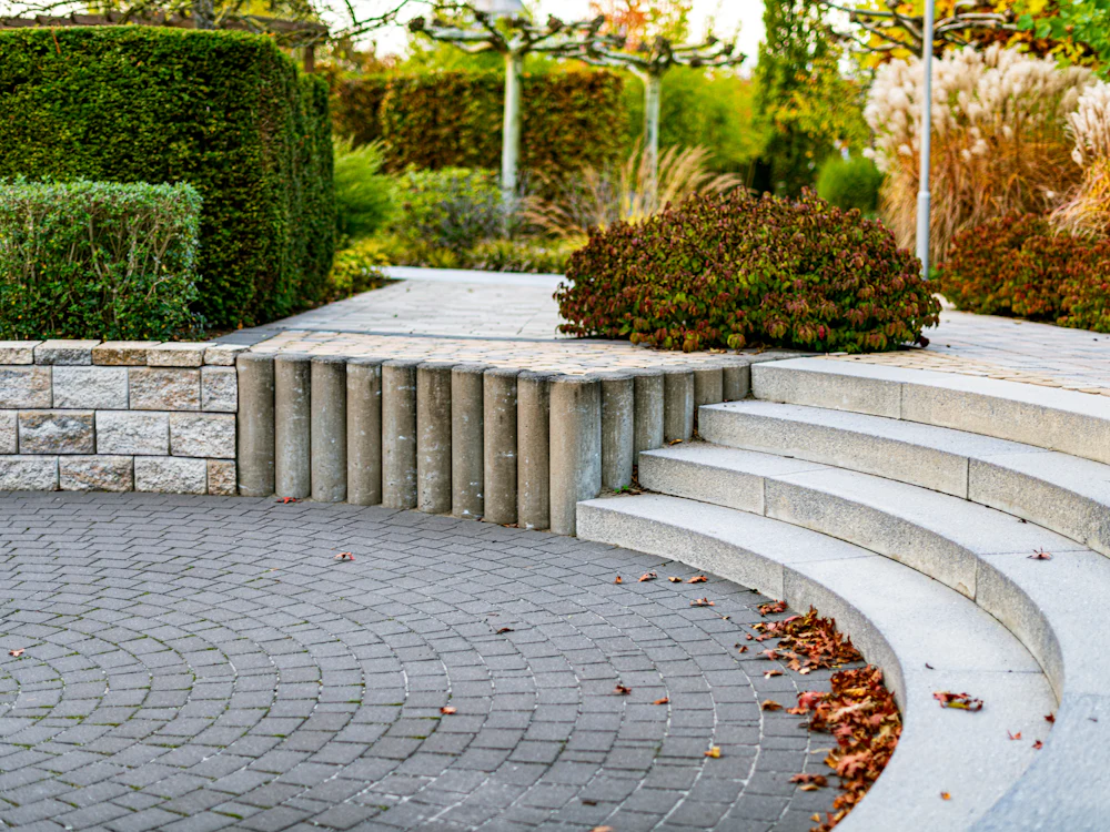 Curved stone steps and cobbled paving beside a block wall
