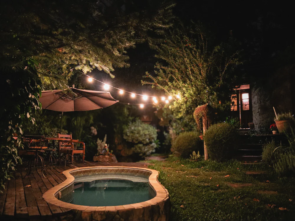 Festoon lights over a small garden pool and timber deck at night