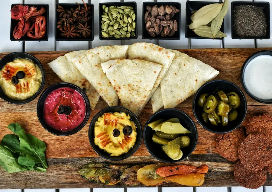 Hummus, baba ghanoush, pickles and flatbread on a board