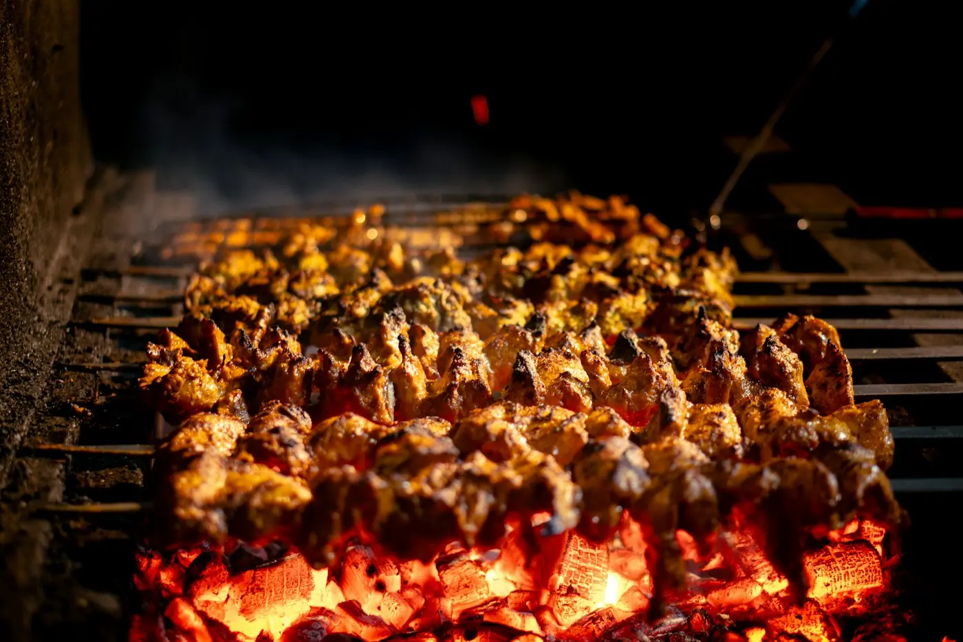 Chicken skewers cooking over glowing charcoal