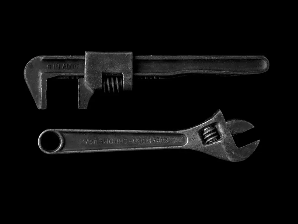 Two vintage plumbing wrenches on a black background