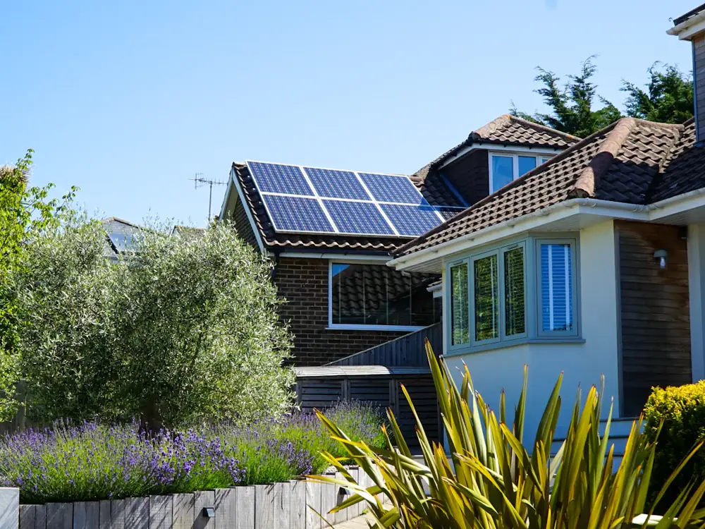 Two-storey home with solar panels among garden trees