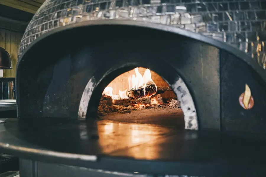 The mouth of a tiled dome oven with the fire burning inside