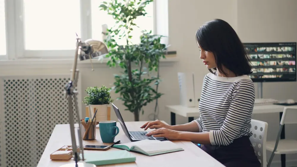 Person working through paperwork at a tidy home desk with a laptop