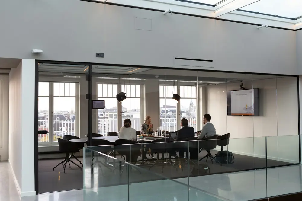 Bright meeting room with clients around a table behind glass walls