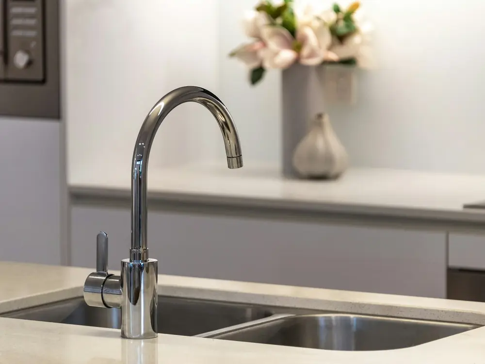 Chrome gooseneck kitchen mixer tap over a stainless sink