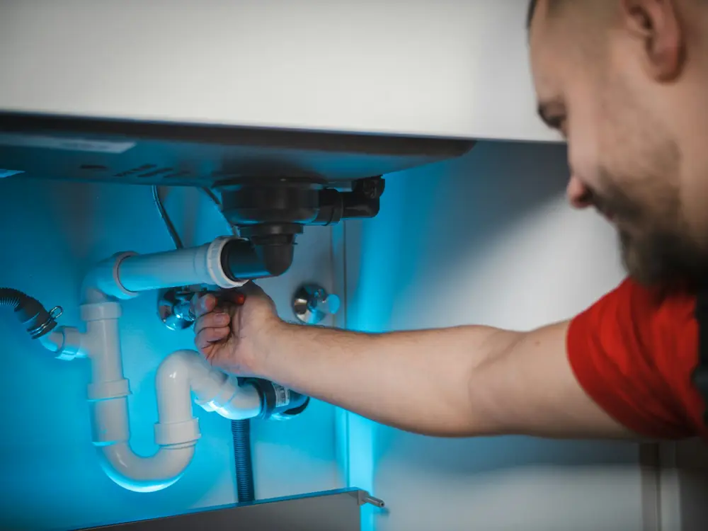 Flowright plumber fixing the waste pipe under a kitchen sink