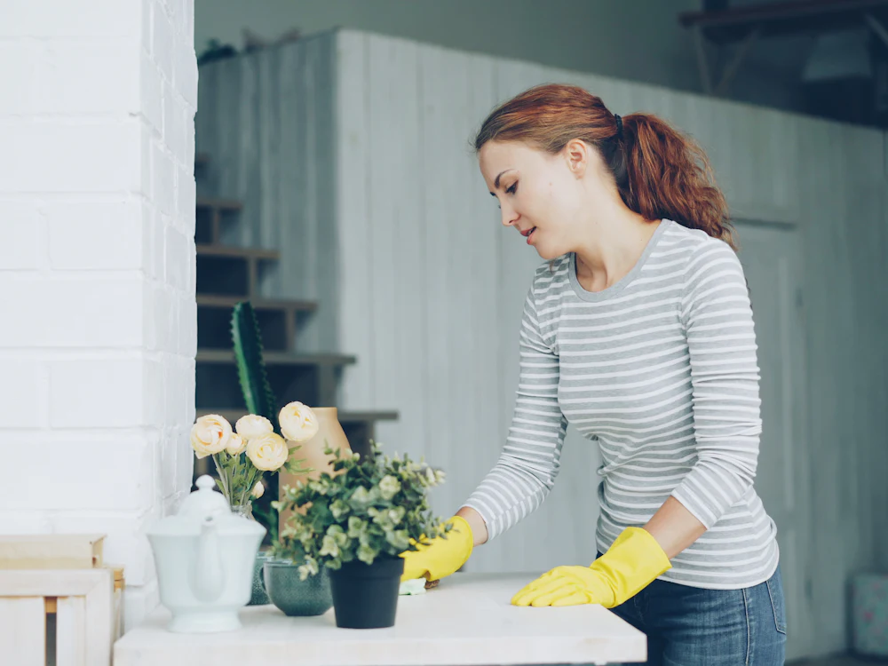 A Fresh Nest cleaner in yellow gloves wiping down a bench