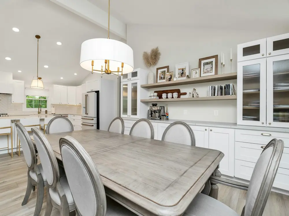 Open kitchen and dining room with shaker cabinets, open shelving and a timber dining table
