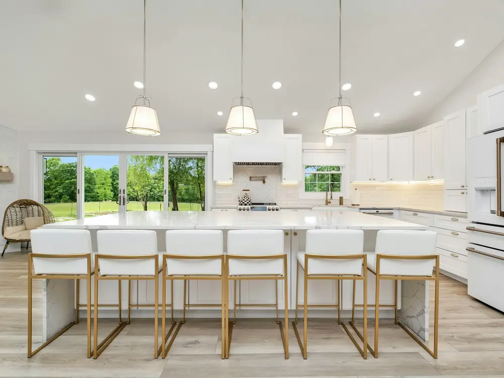 Bright white kitchen with a long island bench, pendant lights and bar stools