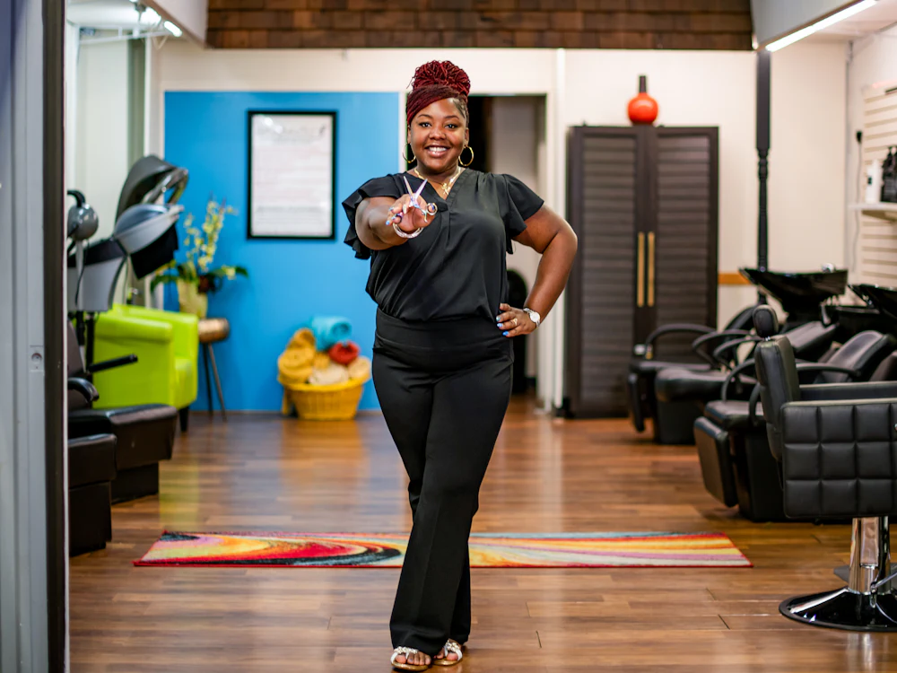 Mia, the owner, standing in the studio holding scissors
