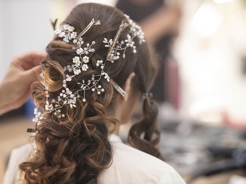 Bridal half-up style with soft curls and a crystal hair vine