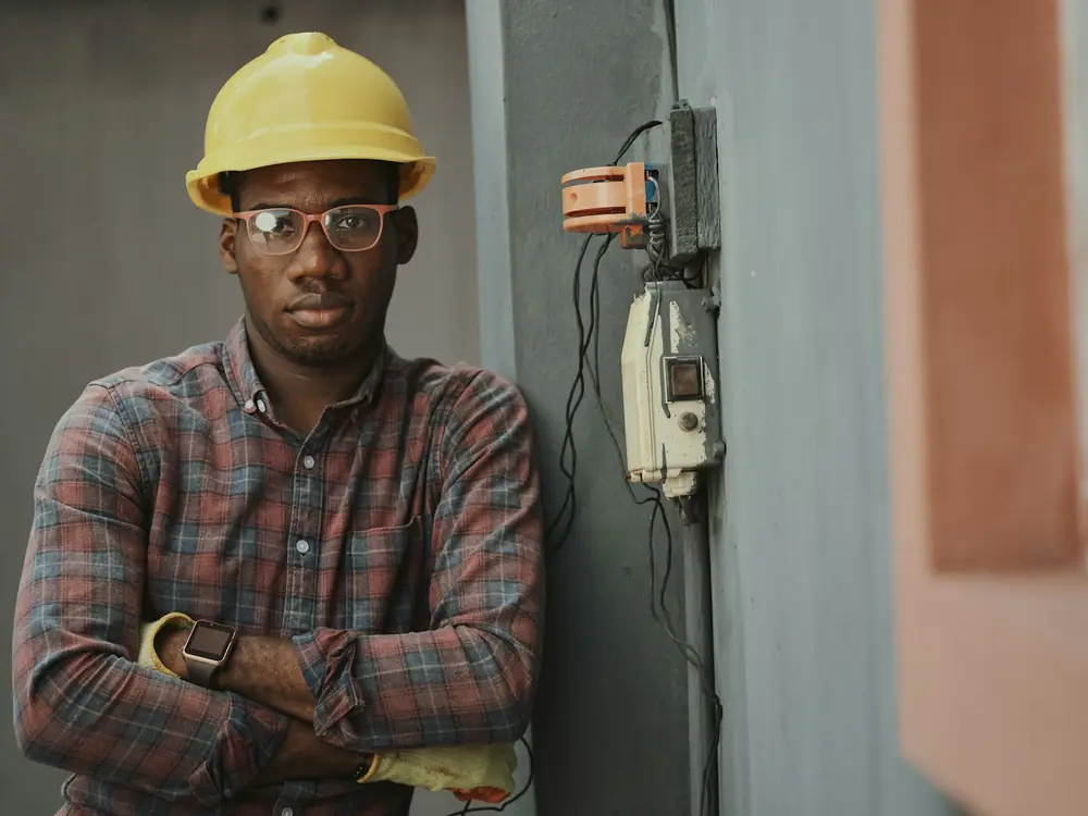 Plumber in a hard hat standing beside plant room equipment
