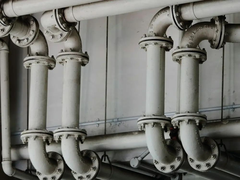 Row of large painted flanged pipes in a building plant room