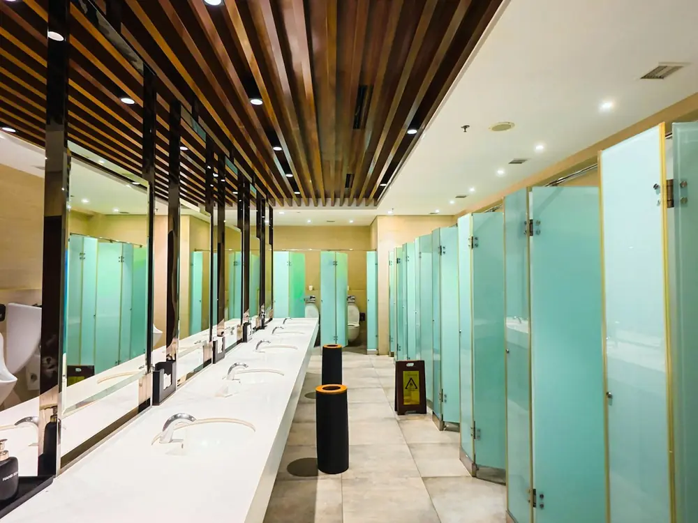 Common area bathroom with a long row of basins and cubicles