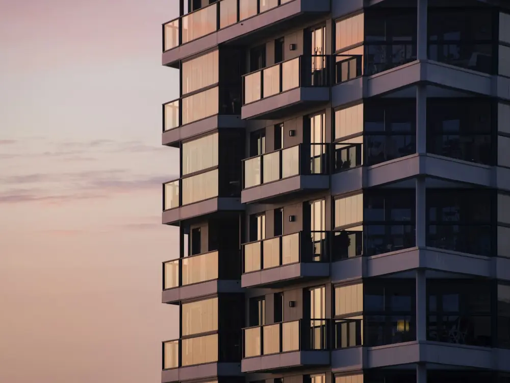 Residential apartment tower with rows of balconies at dusk