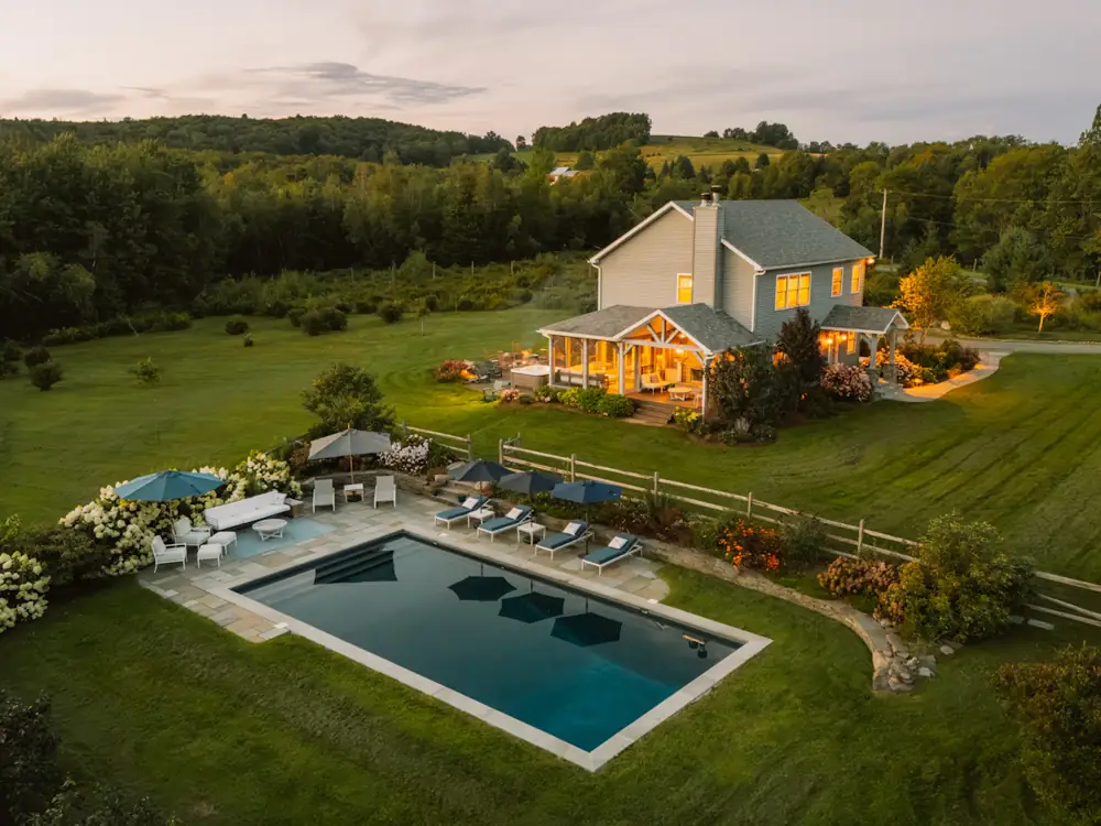 Aerial view of a country home with a pool and gardens at sunset