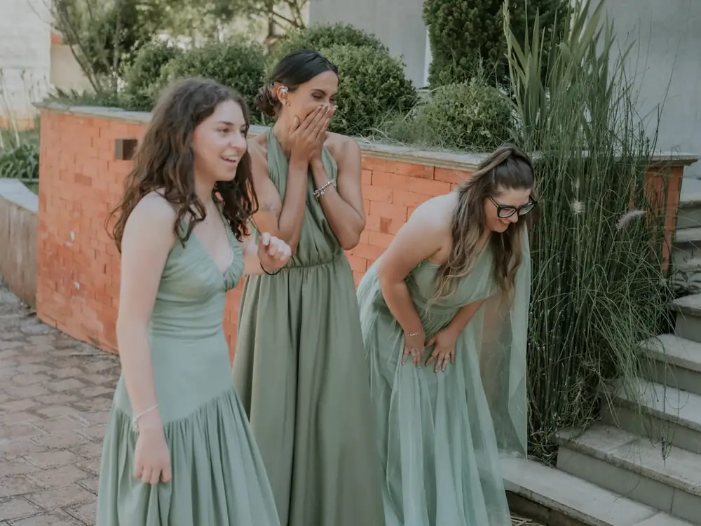 Three bridesmaids in sage green gowns laughing
