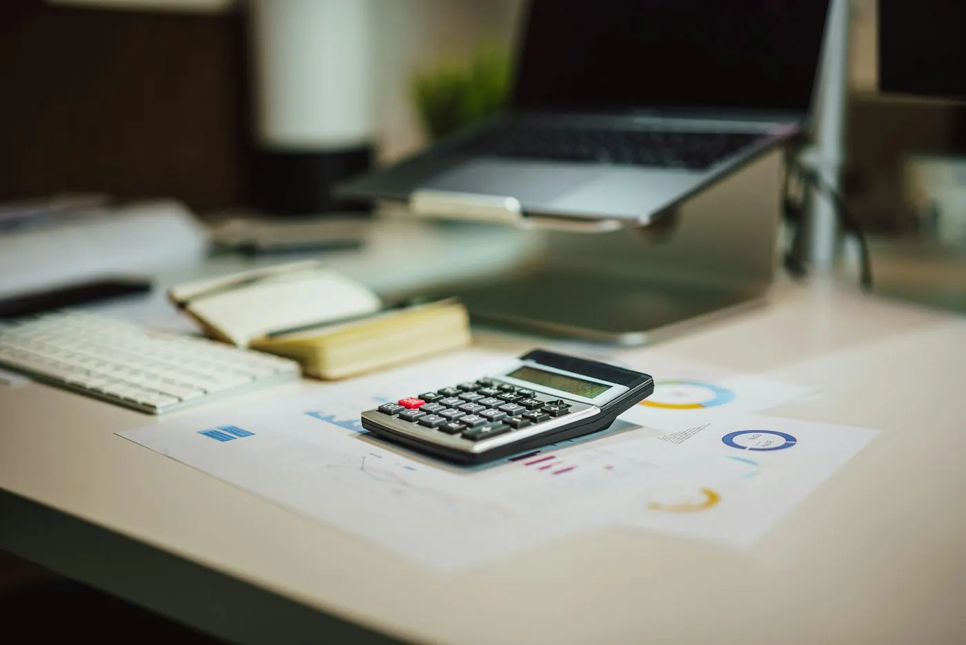Desk calculator beside an open laptop and paperwork
