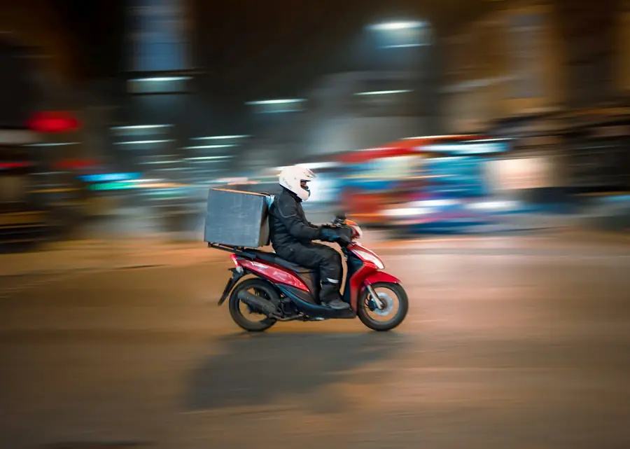 Delivery rider on a red scooter at night