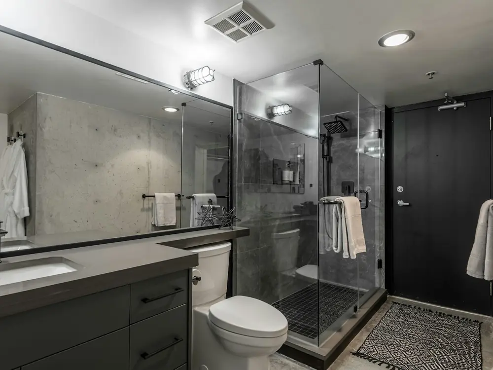 Bathroom with frameless glass shower, concrete-look tiles and dark vanity