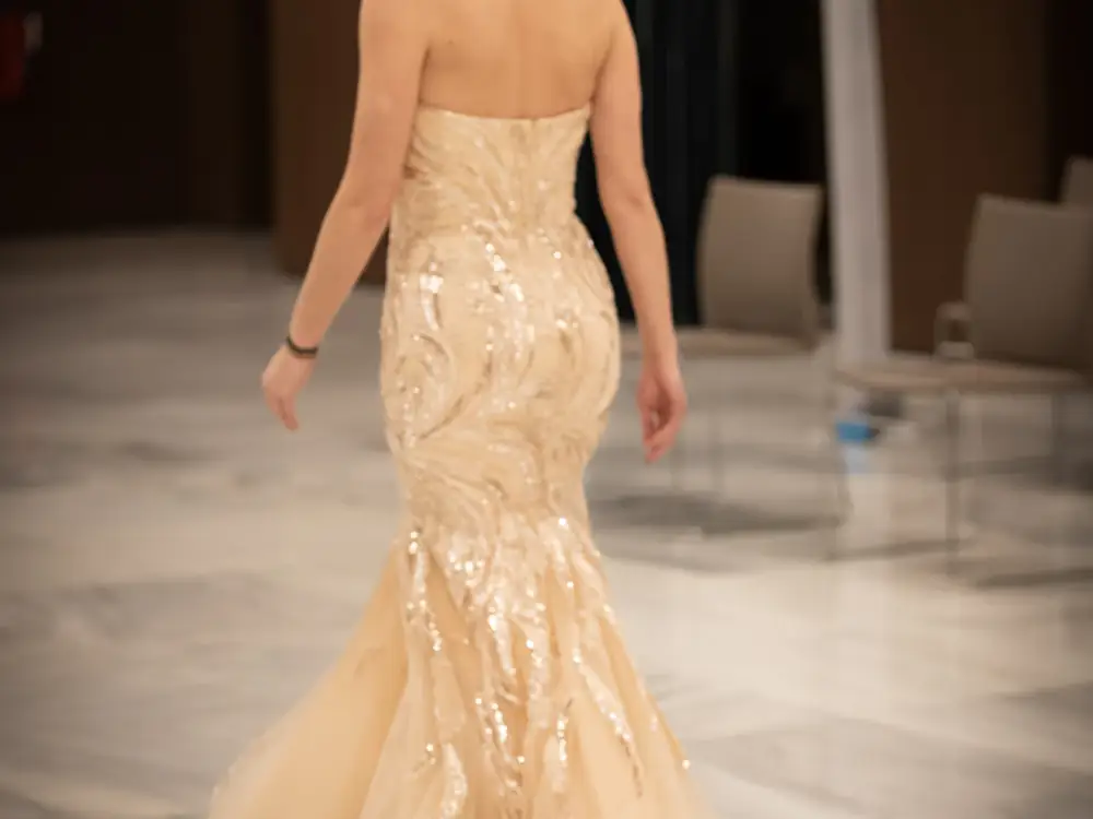 Woman walking away in a champagne sequinned mermaid gown with a tulle skirt