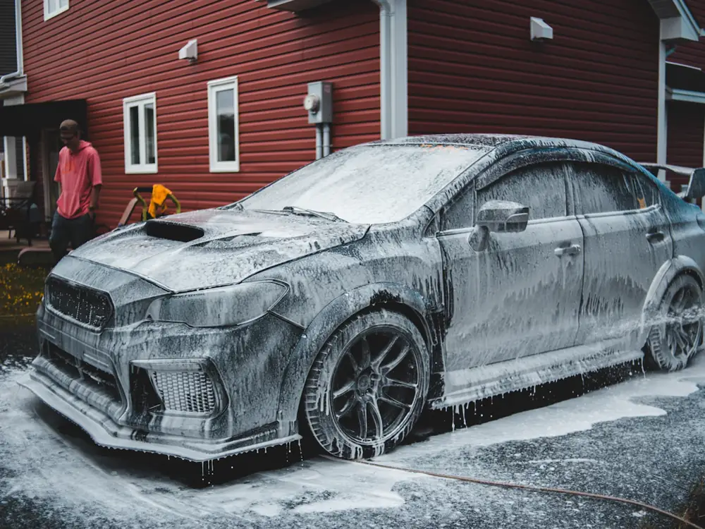 A sedan covered in thick snow foam in a driveway
