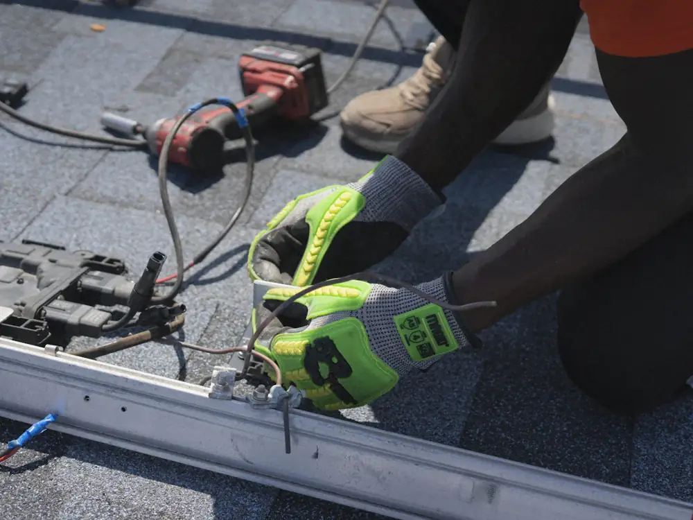 Gloved hands testing solar panel wiring on a roof