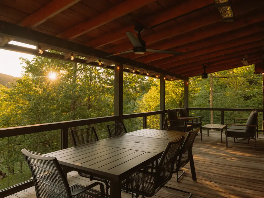 Covered hardwood entertaining deck with outdoor dining table at sunset