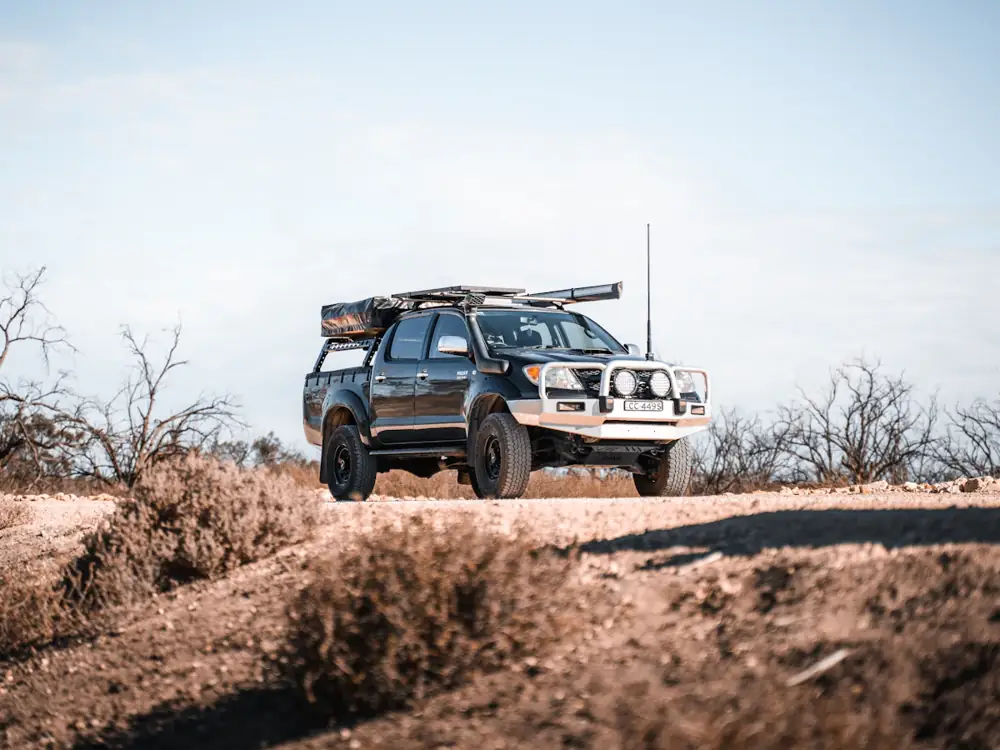 Hilux with rooftop tent and bullbar on a dusty track