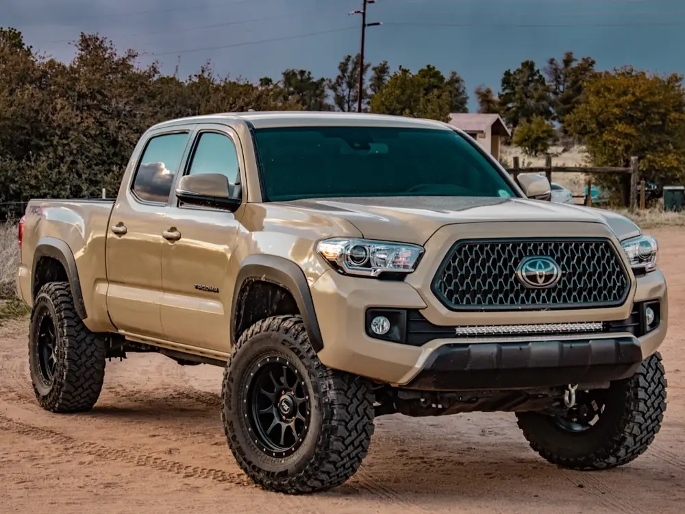 Sand-coloured dual-cab ute on black wheels and off-road tyres