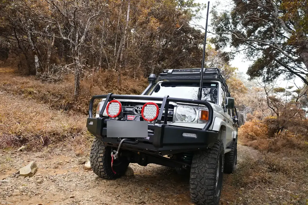 White LandCruiser with bullbar, spotlights and mud-terrain tyres on a dirt track