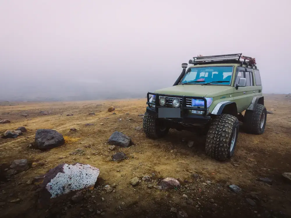 Green LandCruiser with snorkel and roof rack on remote rocky ground