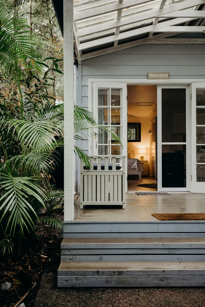 Queenslander verandah glowing with warm lighting through open French doors