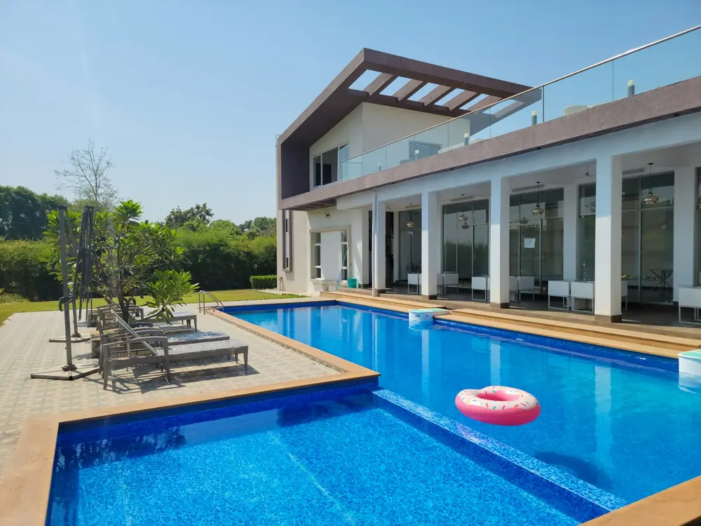 Pool with pale coping and tiled surrounds beside a modern home