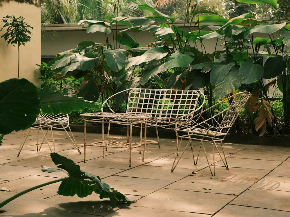 Stone-tiled courtyard alfresco with wire outdoor chairs and tropical plants