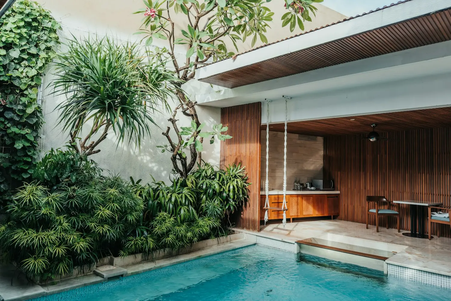 Tiled plunge pool with pale coping, tropical garden and a timber cabana