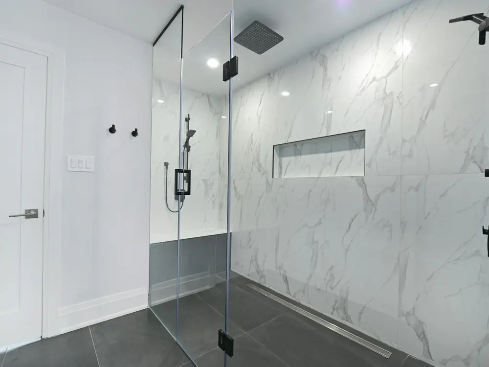 Walk-in shower tiled in large marble-look porcelain with a long wall niche and linear drain