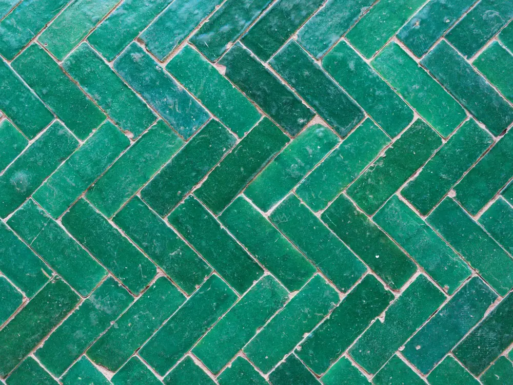 Glossy green zellige tiles laid in a herringbone pattern