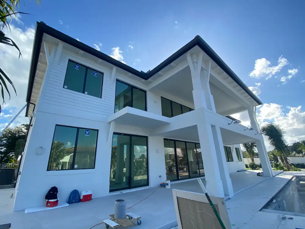 Two-storey white home nearing completion under a blue sky