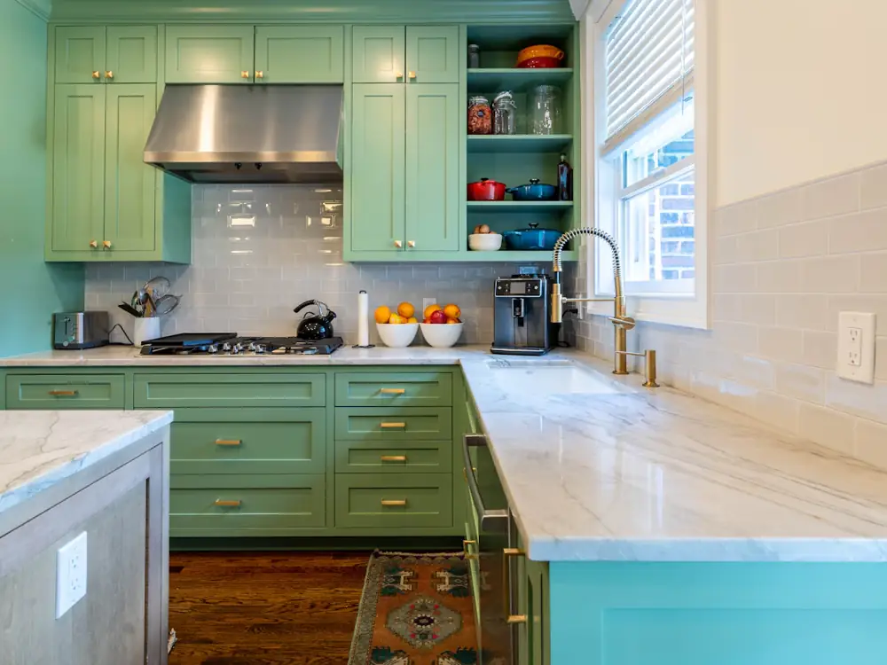 Sage green shaker kitchen with marble-look benchtops and brass tapware
