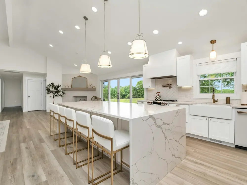 Bright kitchen with a veined marble waterfall island and pendant lights
