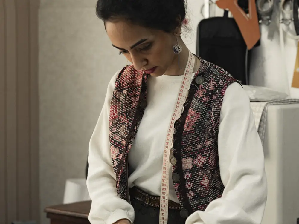 Dressmaker with a tape measure around her neck, working at the bench