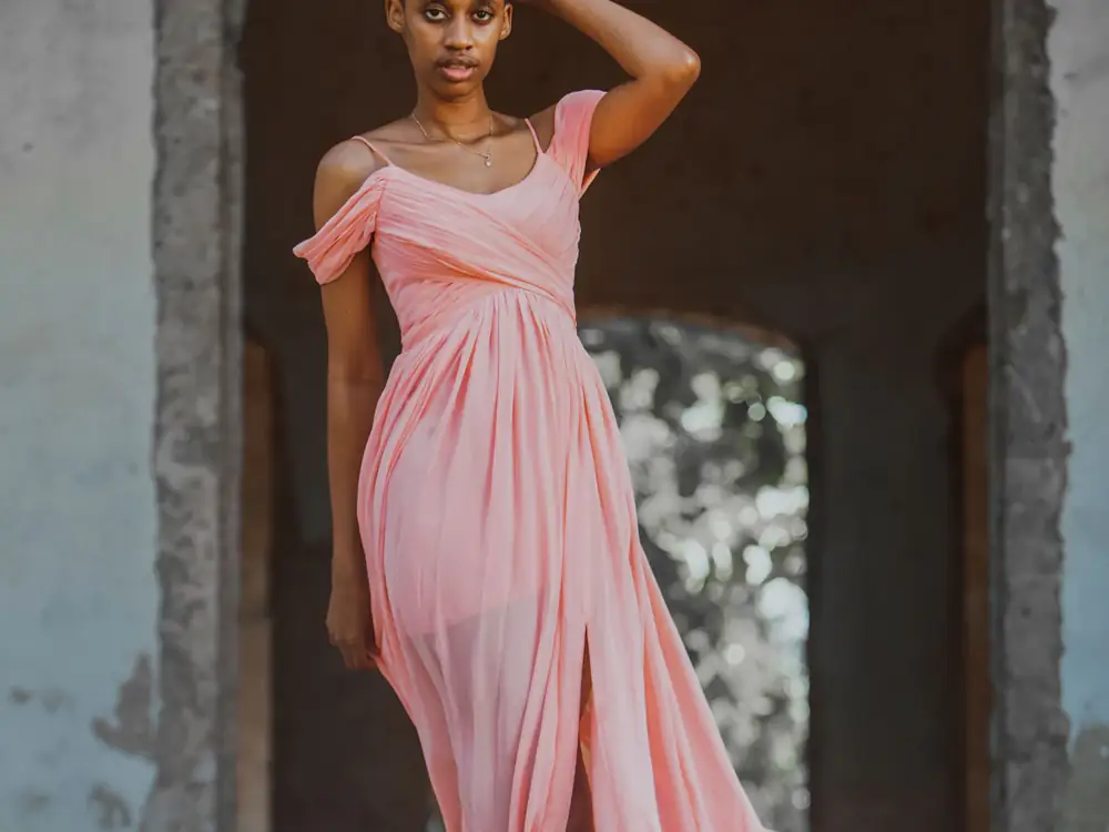 A floor-length blush pink gown with a draped off-shoulder neckline
