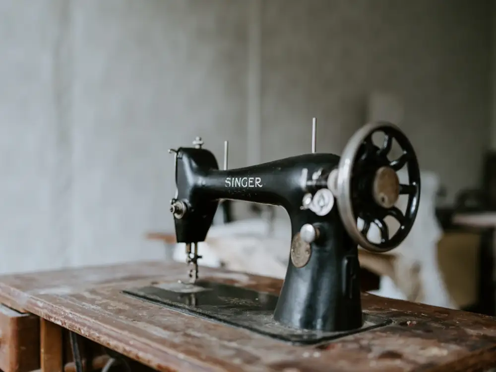 A vintage black Singer sewing machine on a timber table
