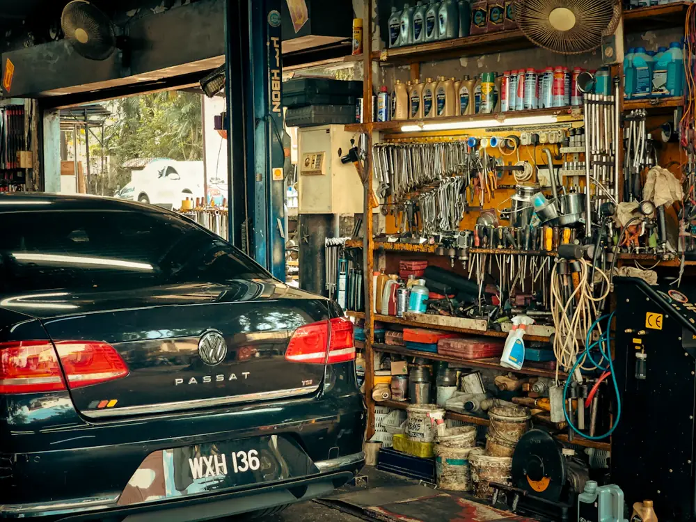 A dark sedan inside a well-stocked workshop, with tools lining the wall