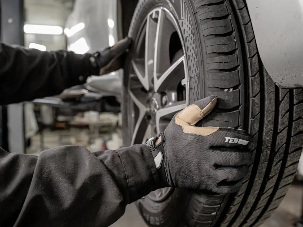 Close-up of a mechanic's gloved hands on a new tyre fitted to an alloy wheel