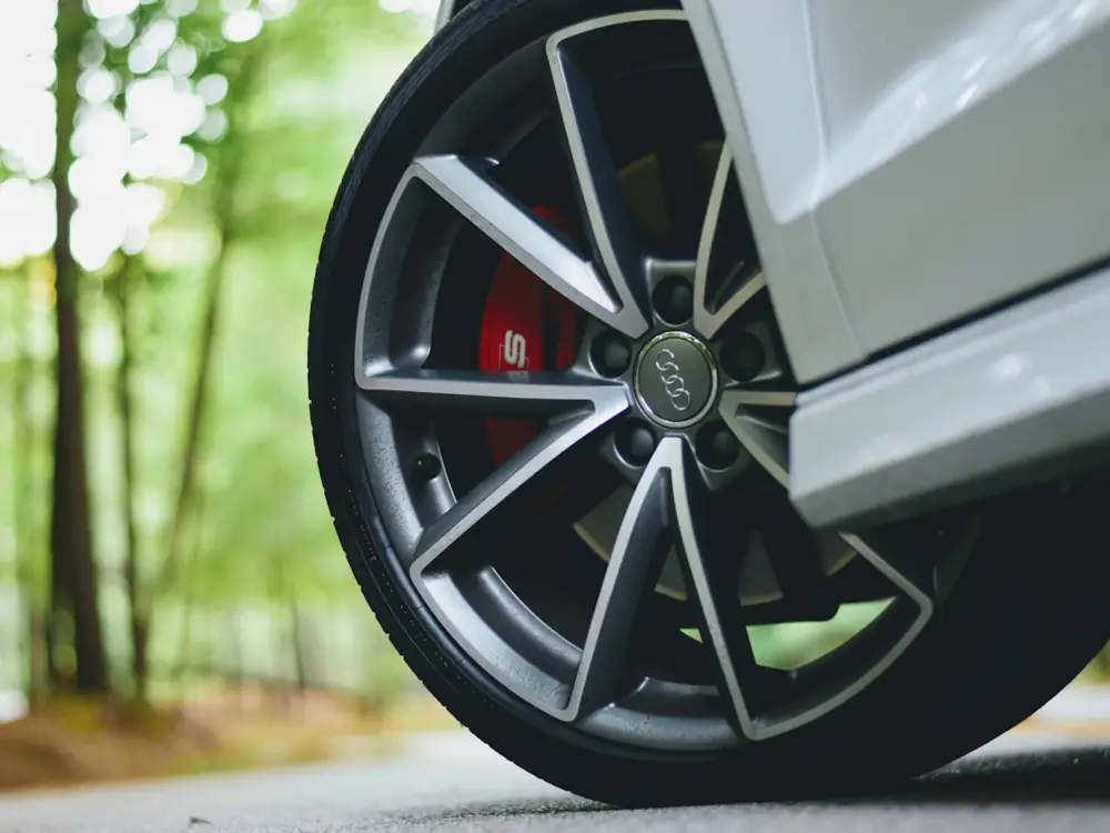 Close-up of a dark alloy wheel with a red brake caliper on a white car