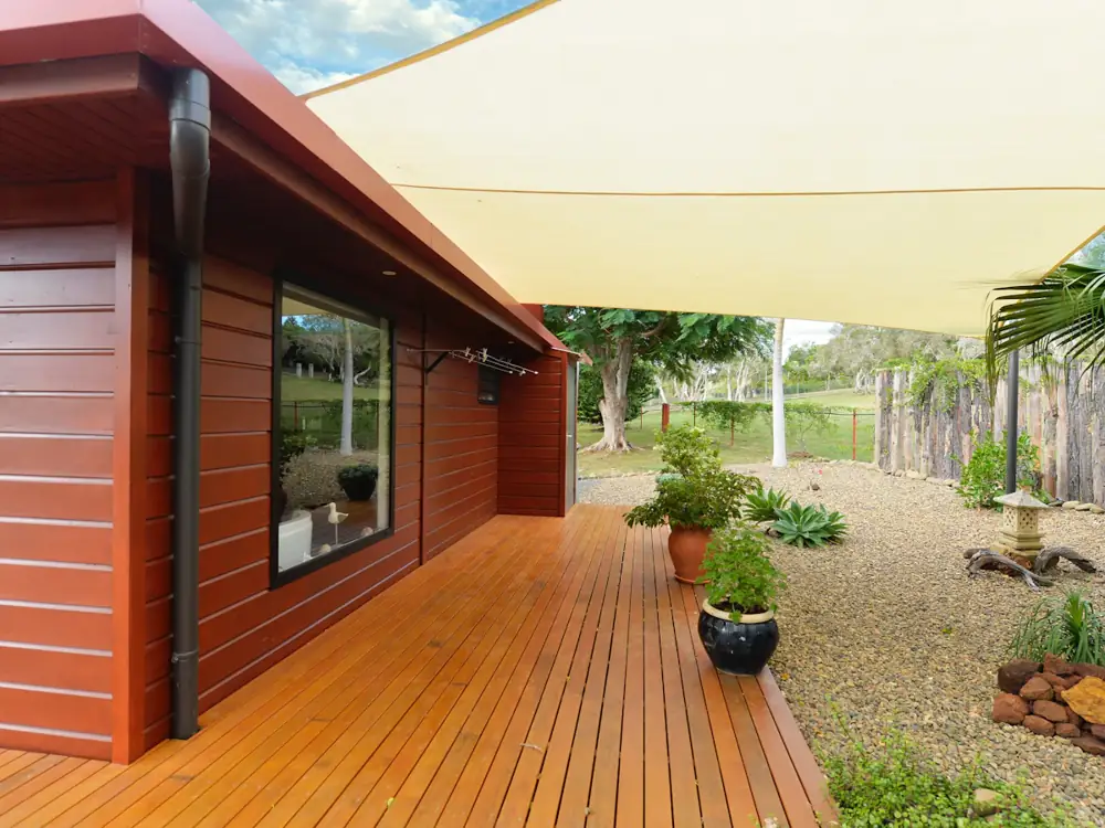 Freshly oiled timber deck running along a red weatherboard house